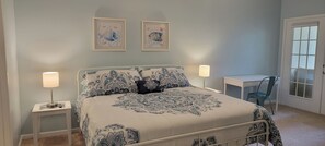 Un dormitorio con una cama, dos mesitas de noche, un escritorio y una silla.