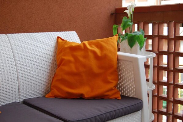 A white textured sofa with a black cushion and an orange pillow.