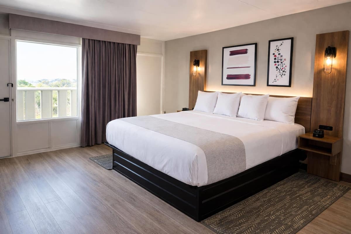 Ein modernes Hotelzimmer mit einem großen Bett, Balkonblick und einem Holzkopfstück.