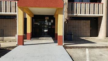 A building with a covered entrance, multiple balconies, and a parking area.