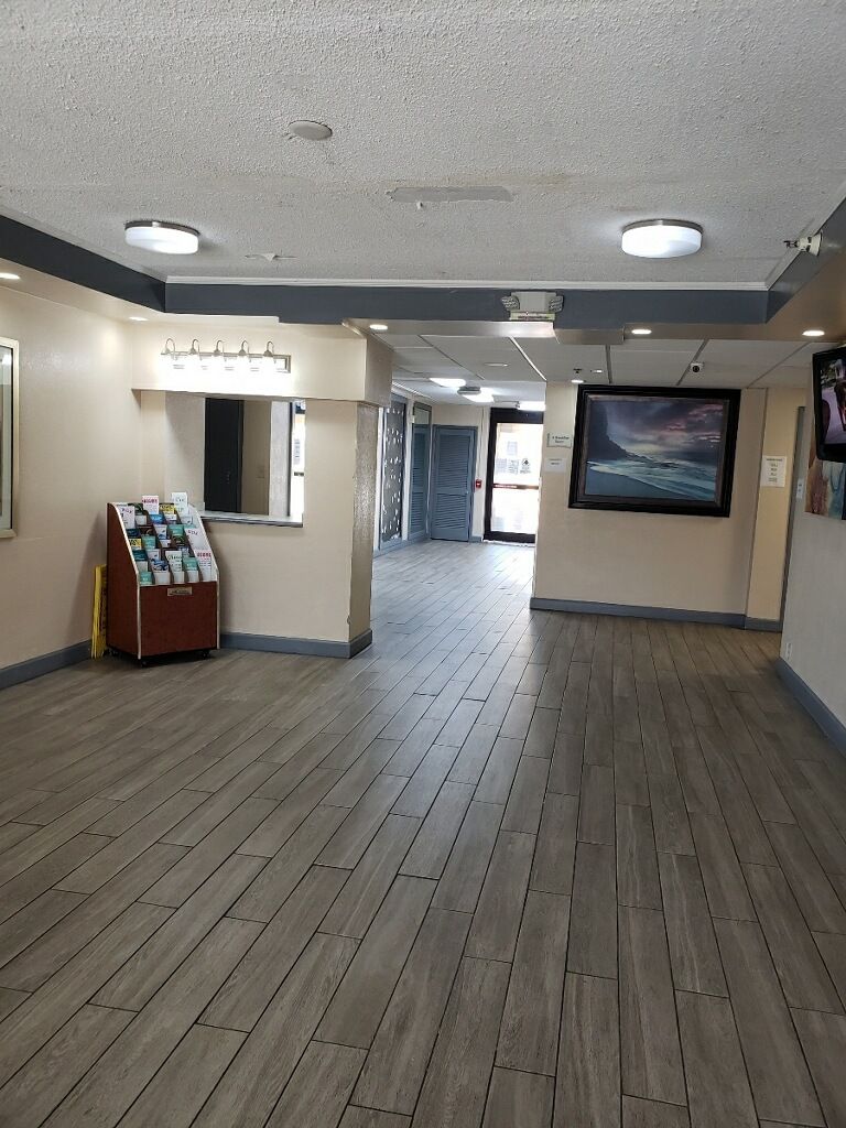 A spacious hallway with wooden flooring, a vending machine, and a large framed picture on the wall.