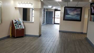 A spacious hallway with wooden flooring, a vending machine, and a large framed picture on the wall.