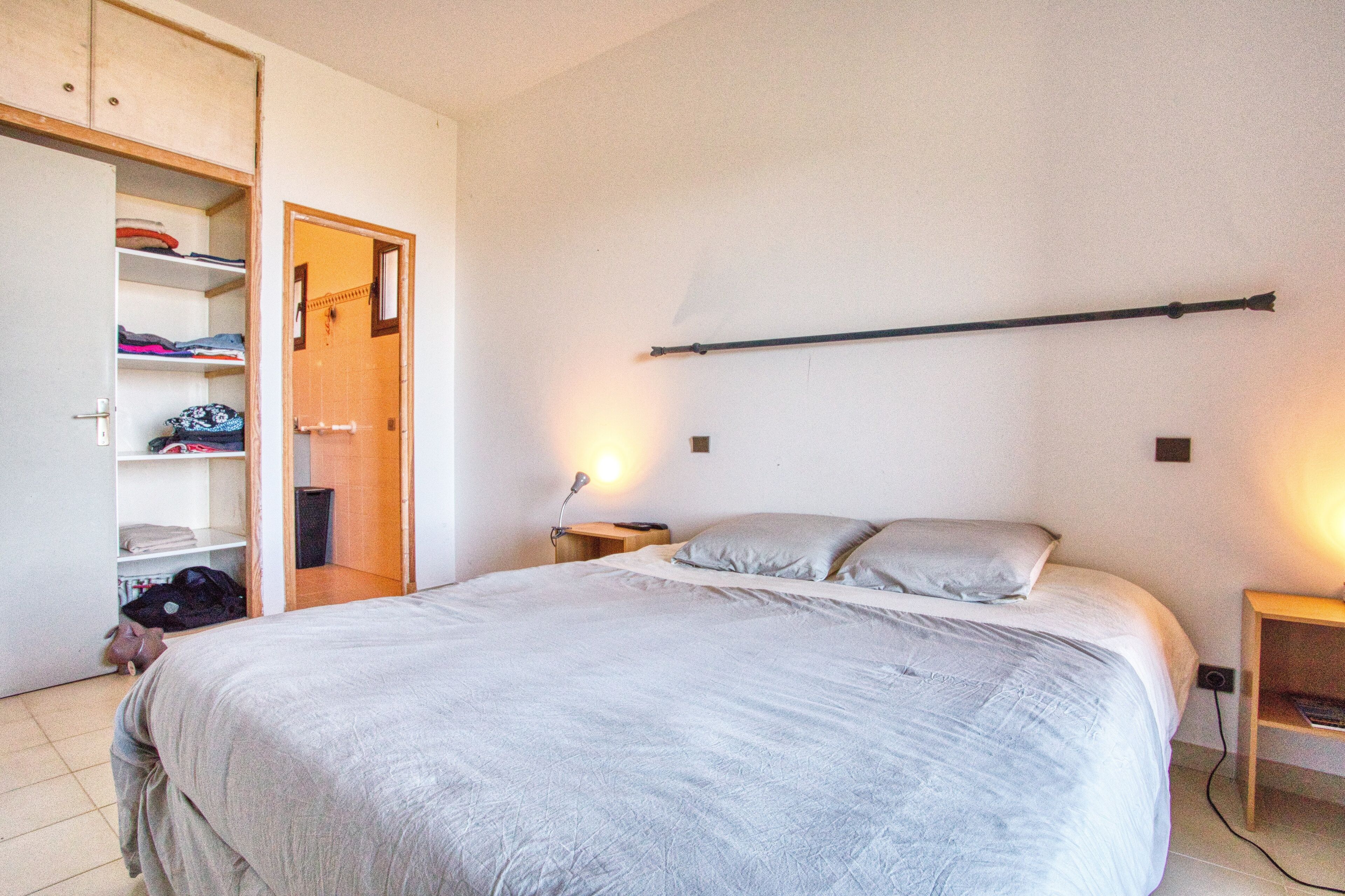 Une chambre à coucher avec un lit, une armoire et une table de chevet.