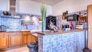 Una cocina con salpicadero de azulejos azules, armarios de madera, una isla central y un microondas.