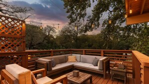 Eine Holzterrasse mit einer Couch, Stühlen und einem kleinen Tisch.