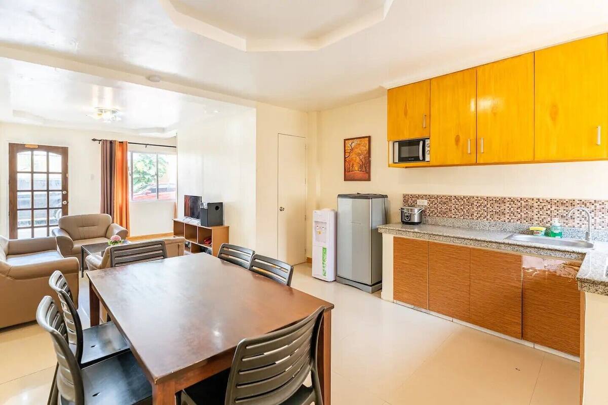 A compact living space with a dining area, kitchenette, and a seating area with a TV.