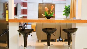 Una cocina moderna con una isla central, tres taburetes de bar e iluminación colgante.