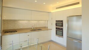 Una cucina moderna con mobili bianchi, un frigorifero in acciaio inossidabile e un forno a due forni.