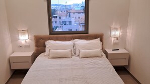 Camera da letto con un letto grande, due comodini, una finestra con vista sulla città e lampade a parete.