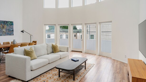 Ein geräumiges Wohnzimmer mit einem weißen Sofa, einem Couchtisch und einem Essbereich mit einem Holztisch und Stühlen.