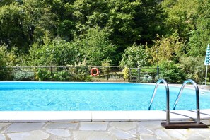 A swimming pool with a lifebuoy, metal pool ladder, and a stone border. - Delightful family Farmhouse with pool, in the woods, 20 km from Florence (Toscana)