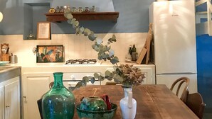 Eine Küche mit Holztisch, Stühlen, einer Pendelleuchte, einem Kühlschrank und einem Herd.