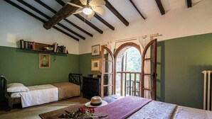 Ein gemütliches Zimmer mit einem Bett, einer hölzernen Kommode, einem Bücherregal und einem Fenster mit Rundbogen.