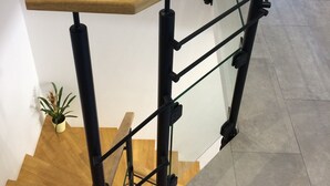 Eine Treppe mit hölzernen Geländern und schwarzen Metallreling.