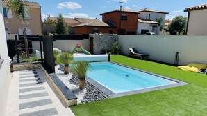 Ein rechteckiger Pool mit umliegender Rasenfläche und einer Steinmauer.