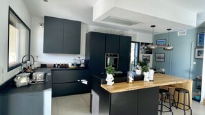 Una cucina moderna con mobili scuri, un'isola centrale con sgabelli e un'ampia finestra che fa entrare luce naturale.