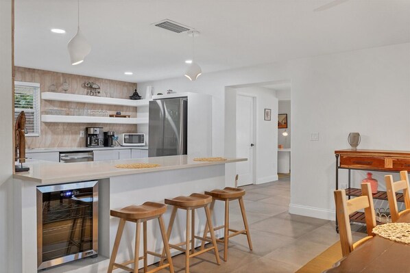 A modern kitchen with a central island, bar stools, a built-in oven, and a refrigerator.