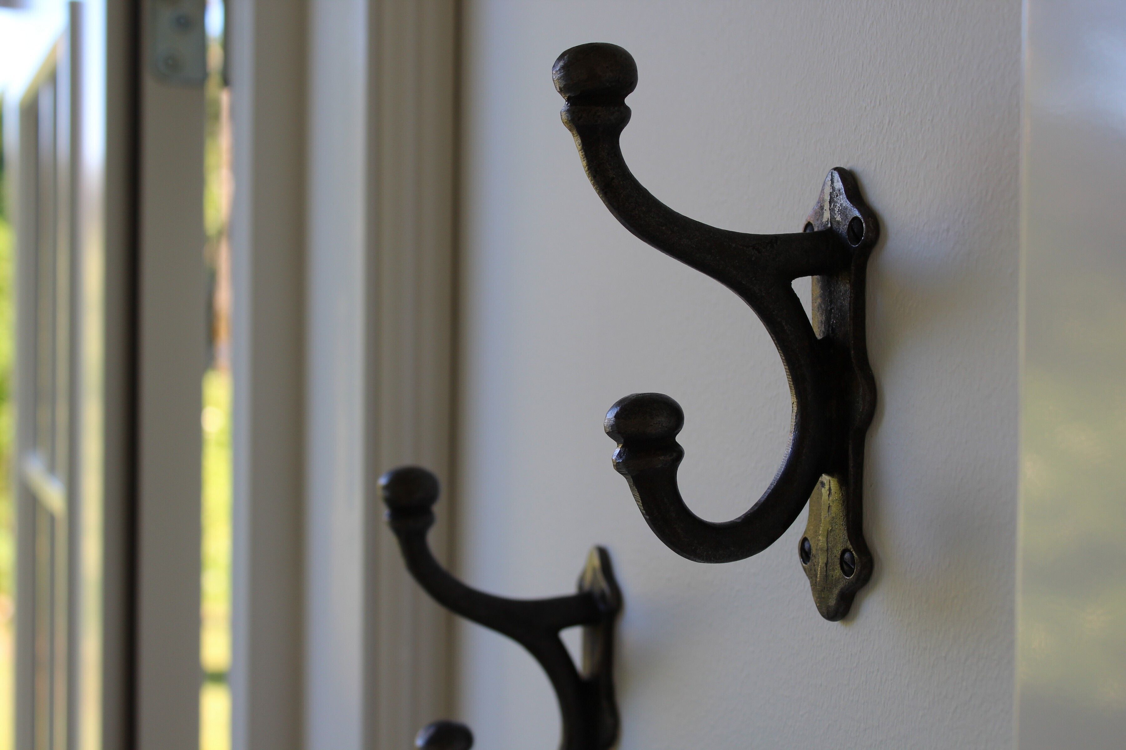 A close-up of a wall-mounted metal hook with a curved design.