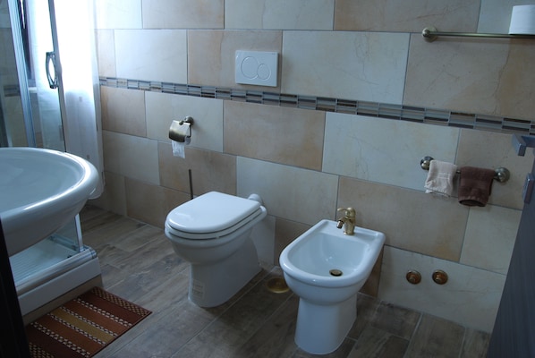 A bathroom with a toilet, bidet, sink, and towel rack.