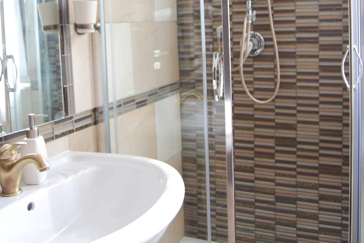 A modern bathroom with a glass-enclosed shower, a white sink, and a mirror.