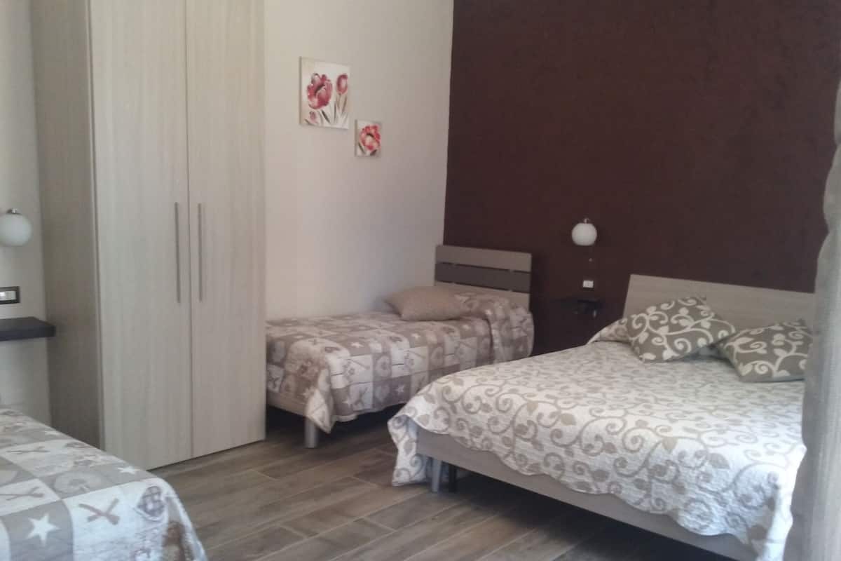 A bedroom with two beds, a wardrobe, and a nightstand.