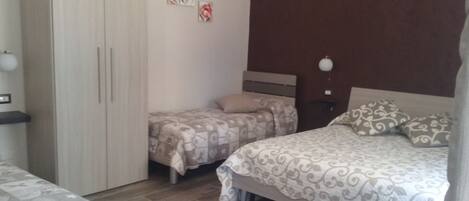 A bedroom with two beds, a wardrobe, and a nightstand.