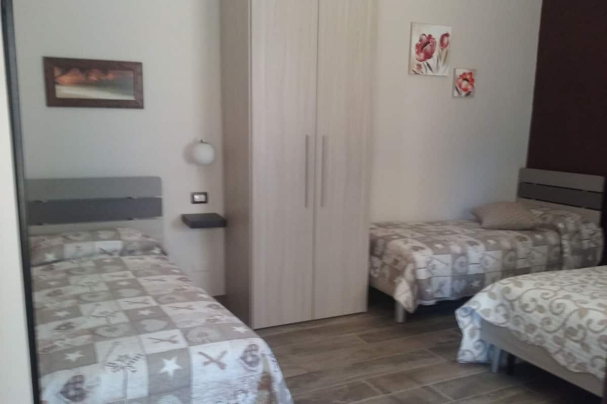 A bedroom with two beds, a wardrobe, and a nightstand.