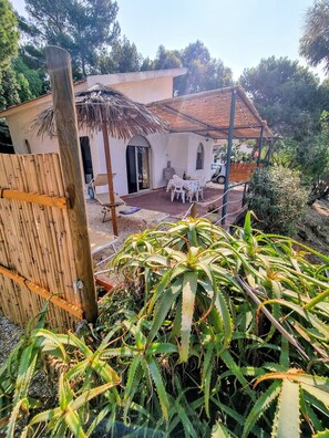 Una casa con patio, techo de paja y fachada blanca.