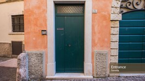 Una puerta verde con un cartel encima, el número '34' en la pared y un letrero que indica 'Entrada Torretta'.