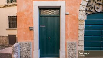Una porta verde con un cartello sopra, il numero '34' sul muro e un segnale che indica 'Ingresso Torretta'.