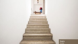 Una escalera que lleva a una plataforma con un banco y un jarrón de flores.