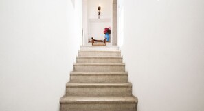 Una escalera que lleva a una plataforma con un banco y un jarrón de flores.