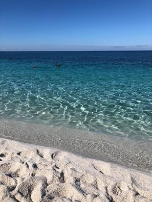 A beach with clear turquoise water and a sandy shore.