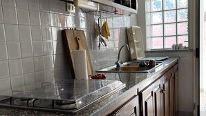 Eine Küche mit einer Granitabdeckung, Holzschränken, einer Edelstahlspüle und einem Fenster mit verzierten Glasscheiben.