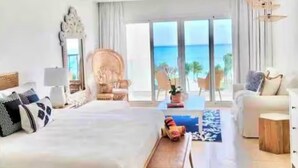 A spacious hotel room with a large bed, a sofa, a coffee table, and a view of the ocean. - G-34B Cap Cana Punta Palmera Beach Studio Ocean View NEW! (Punta Cana)