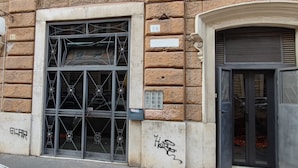 A building facade with a large metal gate, a sign reading "SAKERA," and a number "28" indicating the address. - Maria in Vaticano (Rome)