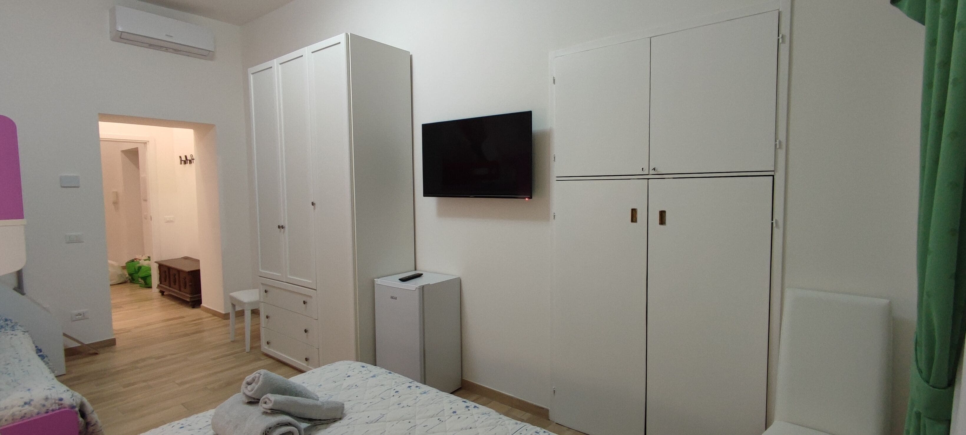 A bedroom with a bed, a wardrobe, a TV, and a heater.