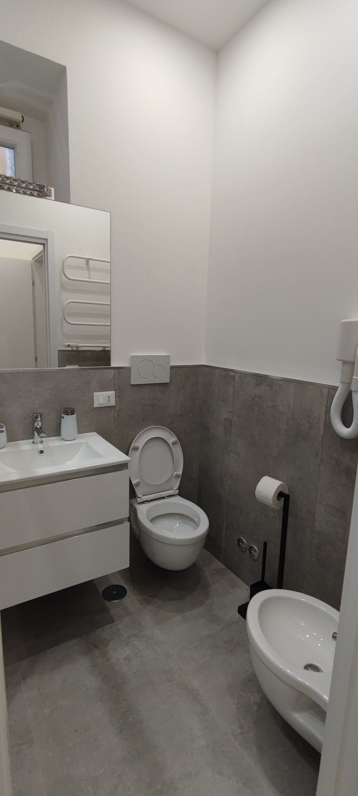 A modern bathroom with a toilet, bidet, and sink.