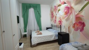 A bedroom with a bed, a chair, a nightstand, and a wall with a floral mural. - Maria in Vaticano (Rome)