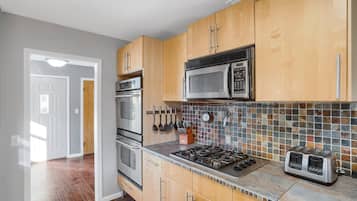 Een koelkast, een oven, een vaatwasser, kookgerei, borden en bestek