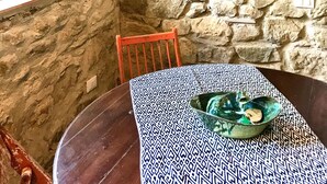 A rustic stone-walled room with a wooden table, a hanging pot, and a window with a view of greenery. - Adorable retreat in the woods with pool, near Florence! (Toscana)