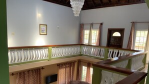 Ampla sala de estar com teto alto, lustre, TV de tela plana e sofá.