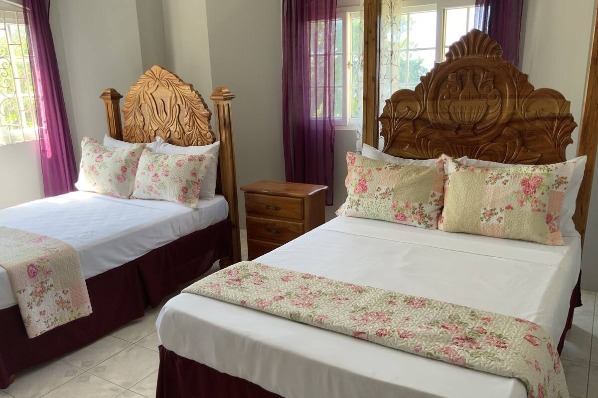 A hotel room with two beds, each with floral bedding and wooden headboards.