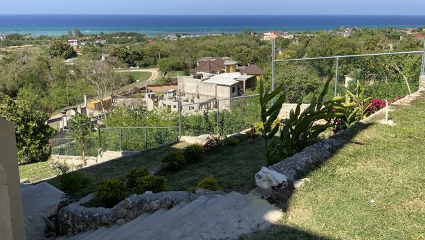 Zona residencial com casas, vista clara do mar e jardim cercado com plantas.