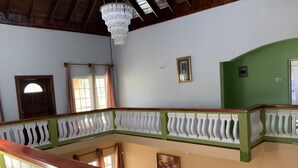 Um quarto com um banco de madeira, um candelabro, uma parede verde e uma porta.