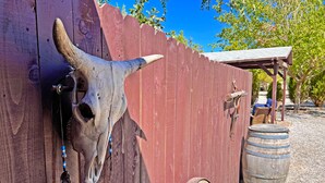 A wooden fence with a cow skull attached to it, a wooden barrel, and a small wooden structure in the background.