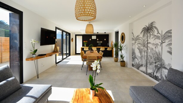 A modern living room with a dining area, a large window, and a wall mural. - A 2 pas de la plage, la Villa YIN (Saint-Pierre-Quiberon)