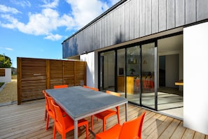 Relax on the outdoor patio with a table and six chairs, adjacent to a building with a kitchen area.