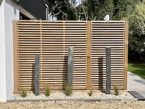 Surrounded by a minimalist fence and lush greenery, this outdoor space offers a serene atmosphere.