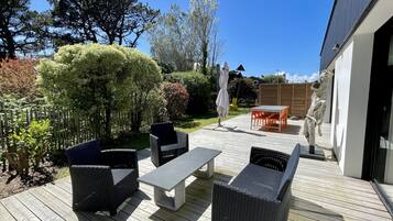 Une terrasse extérieure aménagée avec des meubles en osier, une table et une sculpture.